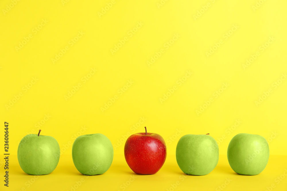 Row of green apples with red one on color background. Be different - obrazy, fototapety, plakaty 
