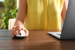 Woman using computer mouse with laptop at table, closeup