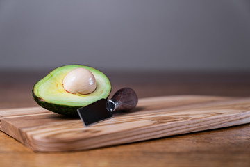 Fresh Organic avocado on a nice, elegant, wooden cutting board on a rustic wooden table with toast and avocado spread