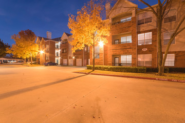 Typical apartment complex with beautiful fall foliage color at blue hour. Rental housing building in suburban Dallas, Texas, USA at evening time