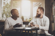 © pavelvinnik - Multiethnic company of men communicates in a cafe