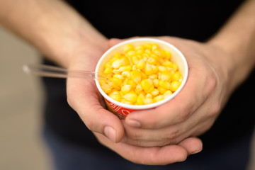 Hands of young man holding cup of deliciously steamed sweet corn