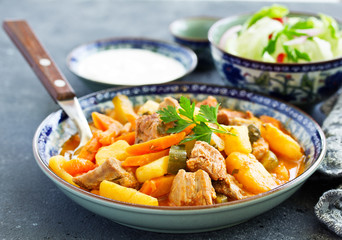 Wall Mural - Beef stew with tomato sauce in a pan on wooden background. azu.