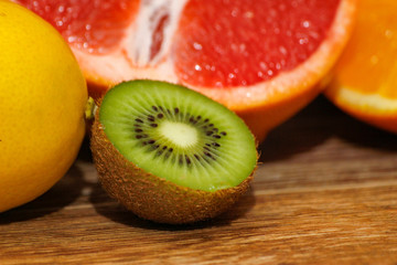 Various raw citrus fruit on wooden table. Close-up of lemon, orange, grapefruit and kiwi.