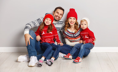 Wall Mural - happy family mother, father and children in knitted hats and sweaters on gray background