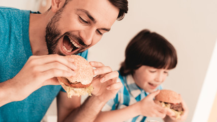 Smiling Son and Father Have Lunch in Kitchen.