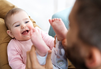 Wall Mural - Unrecognizable father playing with baby daughter sitting indoors, having fun.