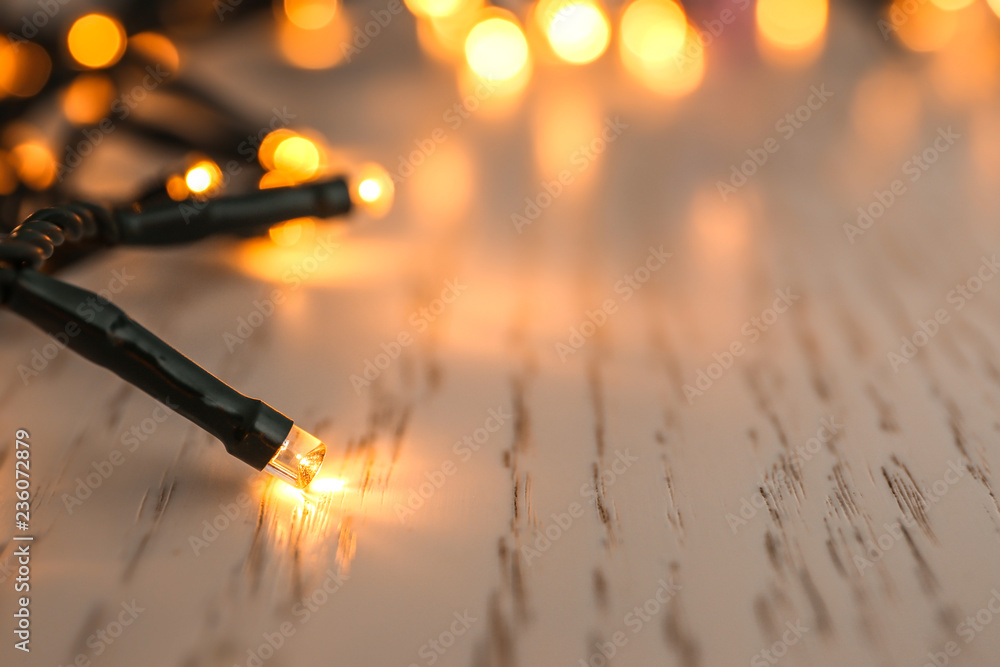 Glowing Christmas lights on table, closeup