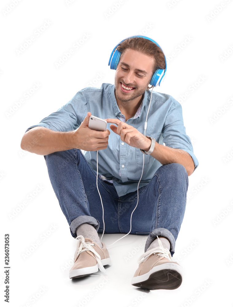 Young man listening to music on white background