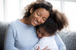 © fizkes - Loving African American mother embracing with preschooler little adorable daughter, sitting together on couch at home, warm relationships parent and child, closeness, love and support concept