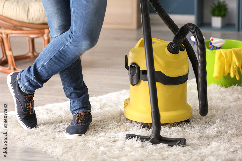 Young man with vacuum cleaner at home