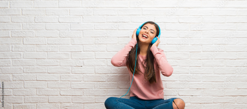 Teenager girl sitting on the floor in a room listening to music with ...