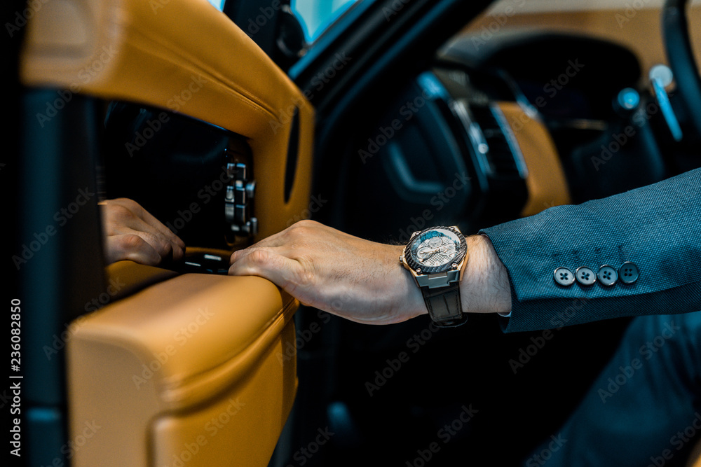 cropped image of businessman with luxury watch closing door while sitting in car - obrazy, fototapety, plakaty 