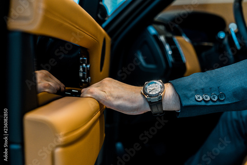 Fotografía cropped image of businessman with luxury watch closing door while sitting in car