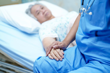 Asian nurse physiotherapist doctor care, help and support senior or elderly old lady woman patient lie down in bed at hospital ward : healthy strong medical concept.