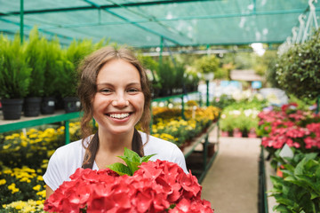 Wall Mural - Happy young woman working in a greenhouse