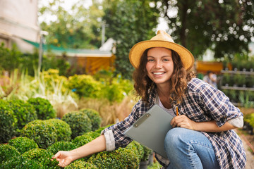 Wall Mural - Happy young woman working in a greenhouse