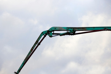 The device of a turquoise loader on the railway. Hydraulic system against the sky