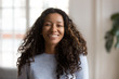 © fizkes - Head shot portrait attractive African American smiling woman, happy pretty female with fluffy curly hair, successful millennial person, standing, posing in living room, looking at camera