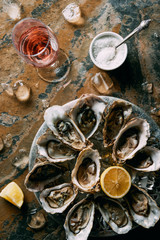 Wall Mural - flat lay with glass of wine, oysters with ice and lemon pieces on grungy tabletop