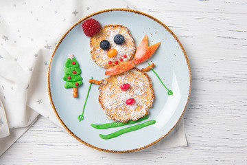 Pancakes in the shape of snowman on ski, Christmas breakfast for kids idea, top view