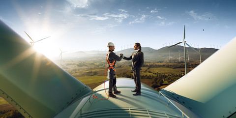 Wall Mural - happy engineer and businessman shake hands after good work. they standing a top of windmill. around 