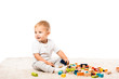 © LIGHTFIELD STUDIOS - cute toddler boy smiling and playing with wooden blocks on carpet isolated on white