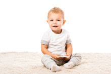 Happy Toddler Boy Sitting On Carpet And Holding Smartphone Isolated On White