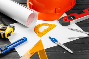 Close up orange hardhat and variety of repair tools with copy space in the middle over wooden  background