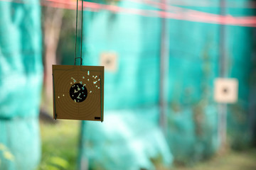 Shooting paper targets with holes in the middle from accurating shoots in a gun shooting range from a shooting practice field. Seeing a green slate a background.