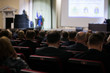 © Семен Саливанчук - Speaker giving a talk on corporate Business Conference. Audience at the conference hall. Business and Entrepreneurship event.