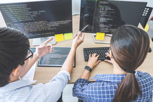 Two professional programmers cooperating at Developing programming and website working in a software develop company office, writing codes and typing data code