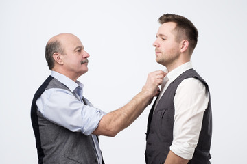 father help son with clothes shir before wedding