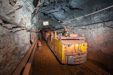 Underground gold iron ore mine shaft tunnel gallery passage with light and electric locomotive loco