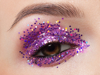 Wall Mural - Close eye with colorful eyeshadow. Macro shot of opened human female eye. Woman with evening beauty makeup. Girl with perfect skin and eyebrow. Women cosmetics, extremely long eyelash and pink glitter