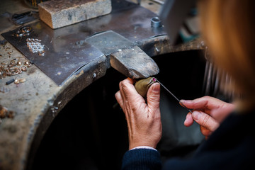 Jeweler working with needle file gold ring  in jewellery workshop