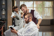 © serhiibobyk - Male client showing haircut in phone in barber shop