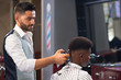 © serhiibobyk - View from side of barber doing trendy haircut in barber shop
