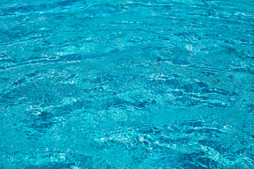 Background of rippled pattern of clean water in a blue swimming pool.