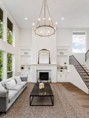 Beautiful Living Room in New Luxury Home with Fireplace. Large Bank of Windows Shows Exterior View of Trees. Vertical Orientation