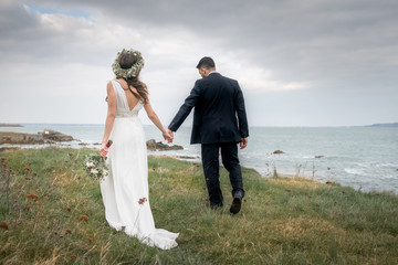 young couple bride groom getting married wedding posed photos at seaside sea beach hairpiece flowers bouquet church