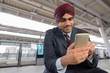 © Ranta Images - Indian businessman using mobile phone at train station