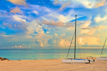 Catamaran on a tropical beach by the turquoise waters of the Caribbean sea, Freeport, Bahamas with stunning clouds in the background at sunset