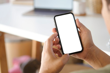 Man hands holding smart phone with blank copy space screen for your text message or information content, male reading text message on cell telephone during in urban setting.