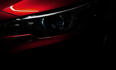 Wall Mural - Closeup headlight of shiny red luxury SUV compact car. Elegant electric car technology and business concept. Hybrid auto and automotive concept. Car parked in showroom or motor show. Car dealership.