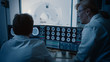 © Gorodenkoff - In Control Room Doctor and Radiologist Discuss Diagnosis while Watching Procedure and Monitors Showing Brain Scans Results, In the Background Patient Undergoes MRI or CT Scan Procedure.