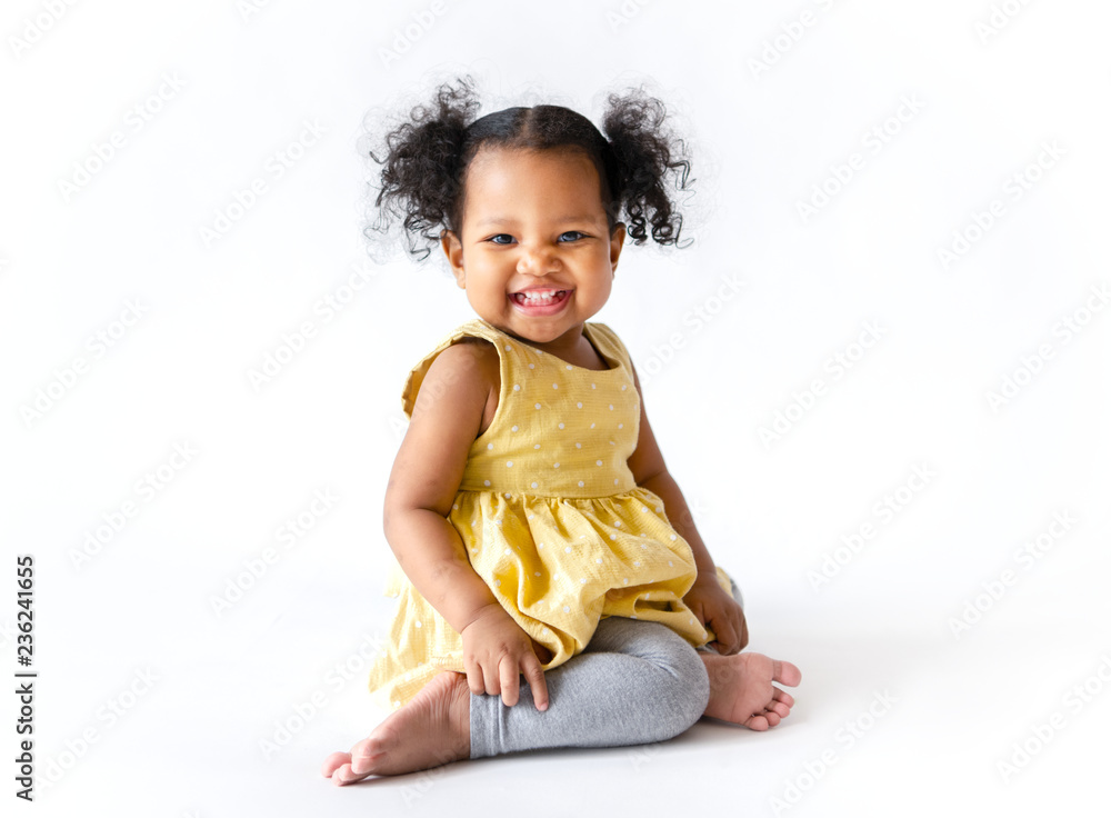 Happy little girl in a yellow dress sitting - obrazy, fototapety, plakaty 