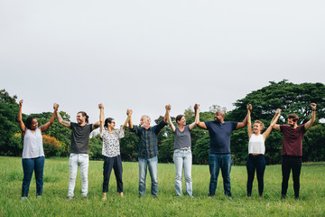 Wall Mural - Happy diverse people holding hands in the park