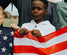 Group Of Diverse Kids Showing A US Flag In A Protest