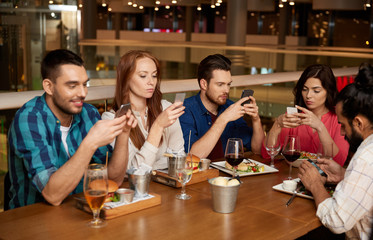 Sticker - leisure, technology, lifestyle and people concept - friends with smartphones dining at restaurant